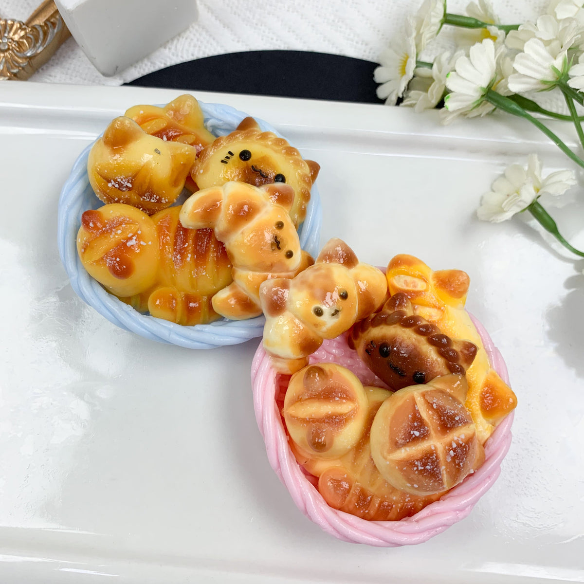 Two small pastries shaped like bears on a white plate with flowers in the background.