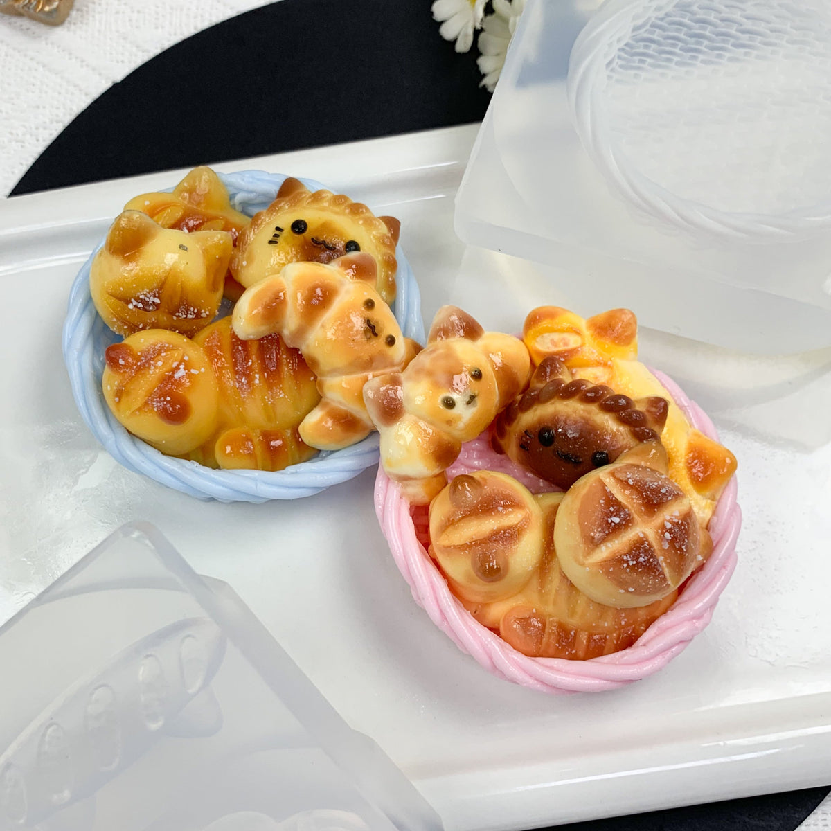 Two small animal-shaped pastries in decorative containers on a white surface.